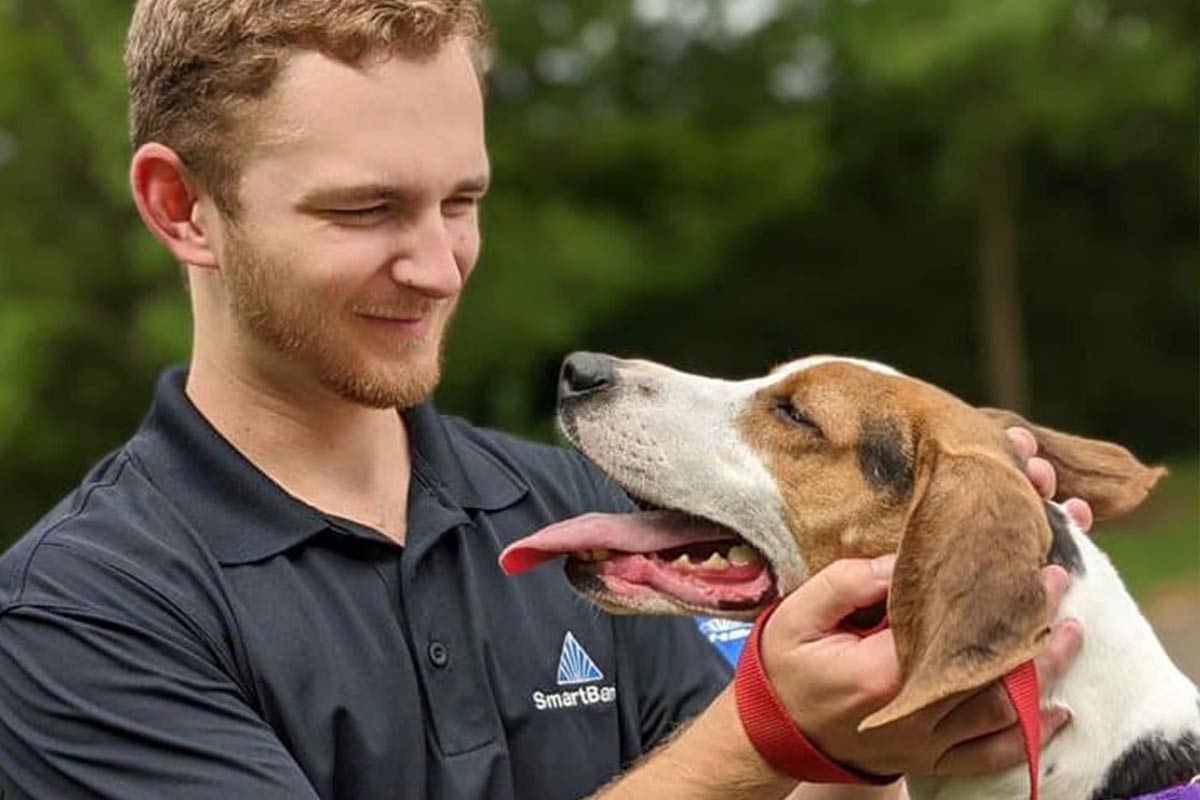 brown and white dog touches noses with a woman in a baseball cap